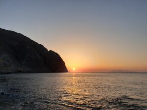 silhouette of mountain beside sea during sunset