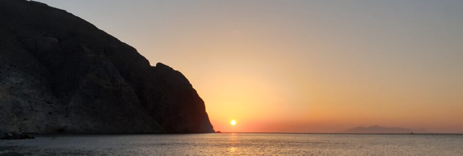 silhouette of mountain beside sea during sunset
